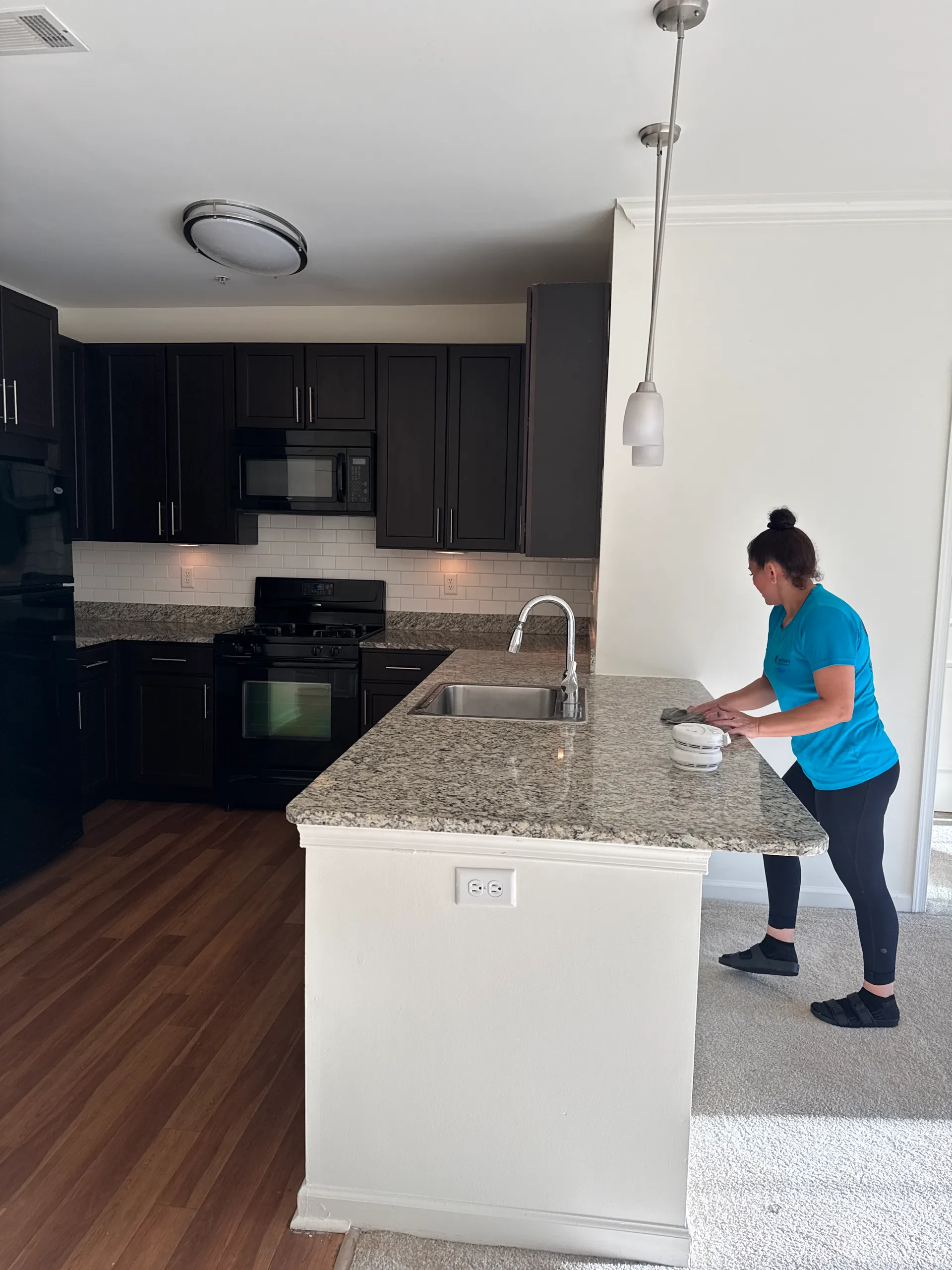 Una integrante del equipo de Maritza's, con camisa de la empresa, limpia una encimera de granito en una casa de Long Island